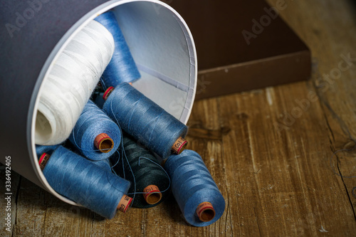 Colored spool of thread falling out of box. Wooden table. Sewing concept. photo