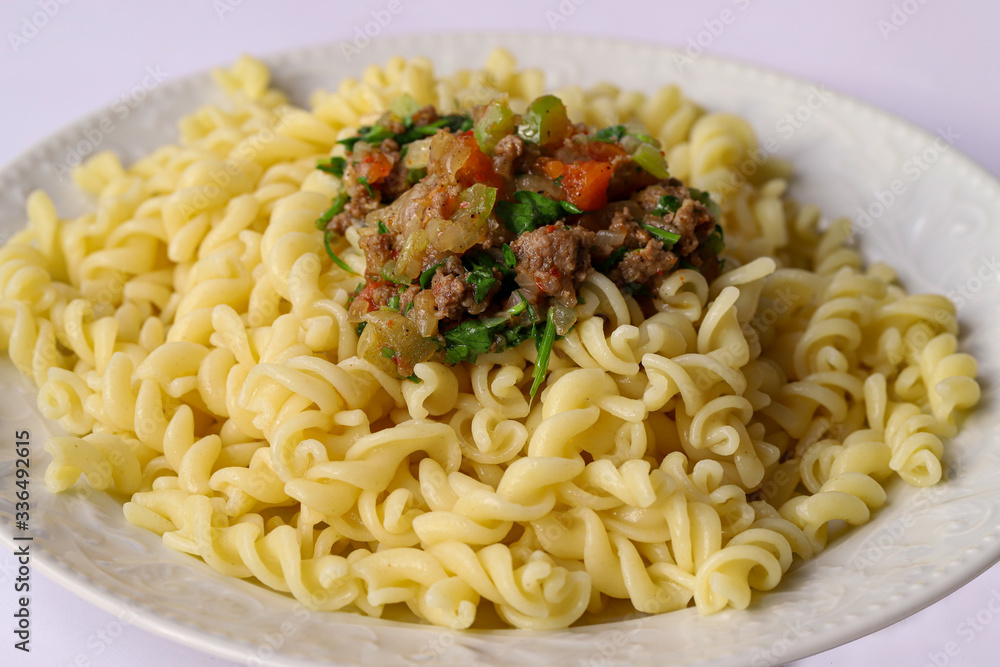 Turkish style ground beef, tomato, onion and parsley pasta in a white plate. Turkish style ground beef, tomato, onion and parsley pasta in a white plate.