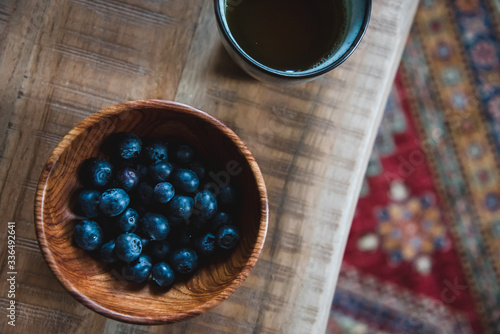 Fresh healthy snack - blueberries in the wooden bowl and cup of tea