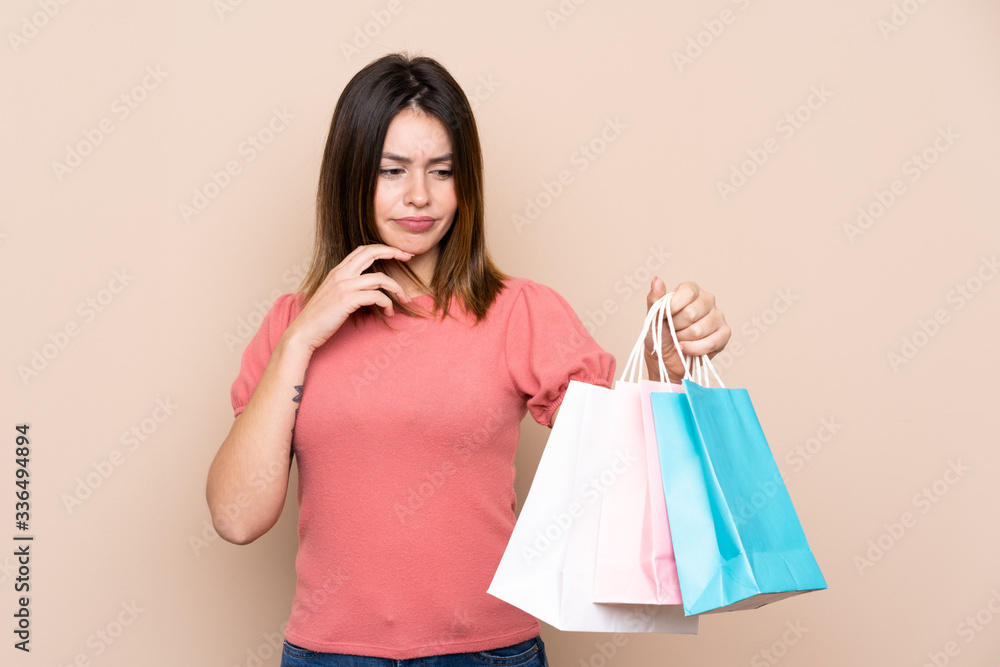Young woman with shopping bag over isolated background with sad expression