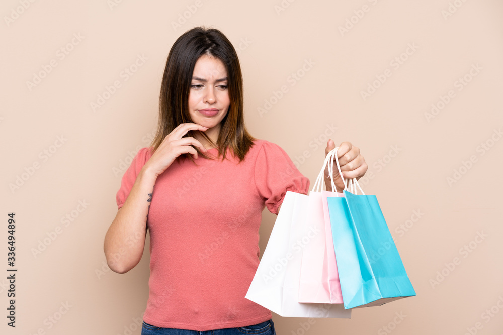Young woman with shopping bag over isolated background with sad expression Young woman with shopping bag over isolated background with sad expression