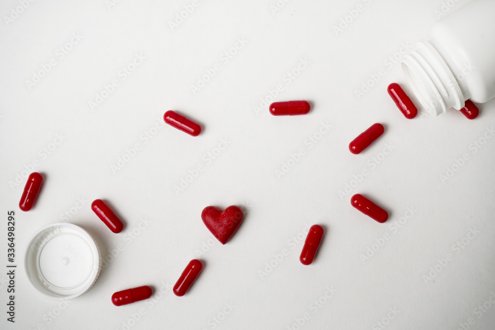 Scattered red pills on a white background. Vitamins for heart health. Scattered red pills on a white background. Vitamins for heart health.