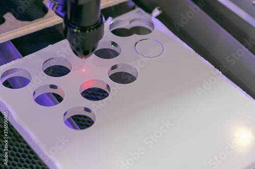 Details of an industrial CNC laser cutting machine. Drilling holes in plexiglass panel with a hot plasma pinhead. Automation concept, robotic arm, future jobs concept. 