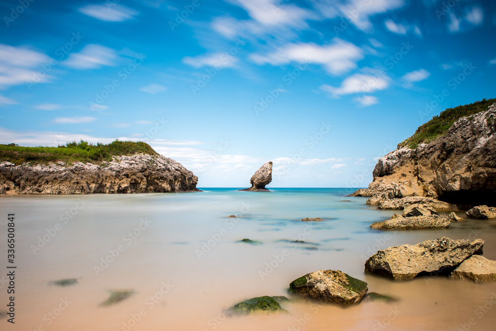 Rocky seashore on a sunny day. Coastal landscape, wild nature, small picturesque bay, beautiful rock in the sea. Playa de Buelna, Asturias, Spain