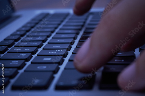 Hands of a man typing on a keyboard of a laptop.