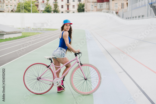 Cycling and fitness. Young beautiful fit woman with perfect body in sportswear with the bike outdoors on the track. Sportive and healthy lifestyle, cyclist working out, training, fashion, beauty.