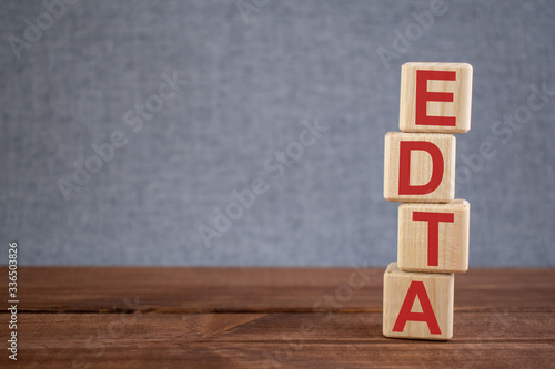 Abbreviation EDTA (ethylene diamine tetraacetate) text acronym on wooden cubes on dark wooden backround. Medicine concept.
