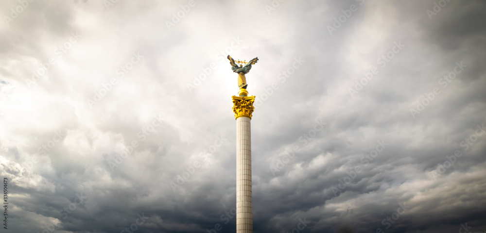 View up to Independence monument on Independence square in Kyiv with dramatic clouds around. Blank space panoramic background image. View up to Independence monument on Independence square in Kyiv with dramatic clouds around. Blank space panoramic background image.