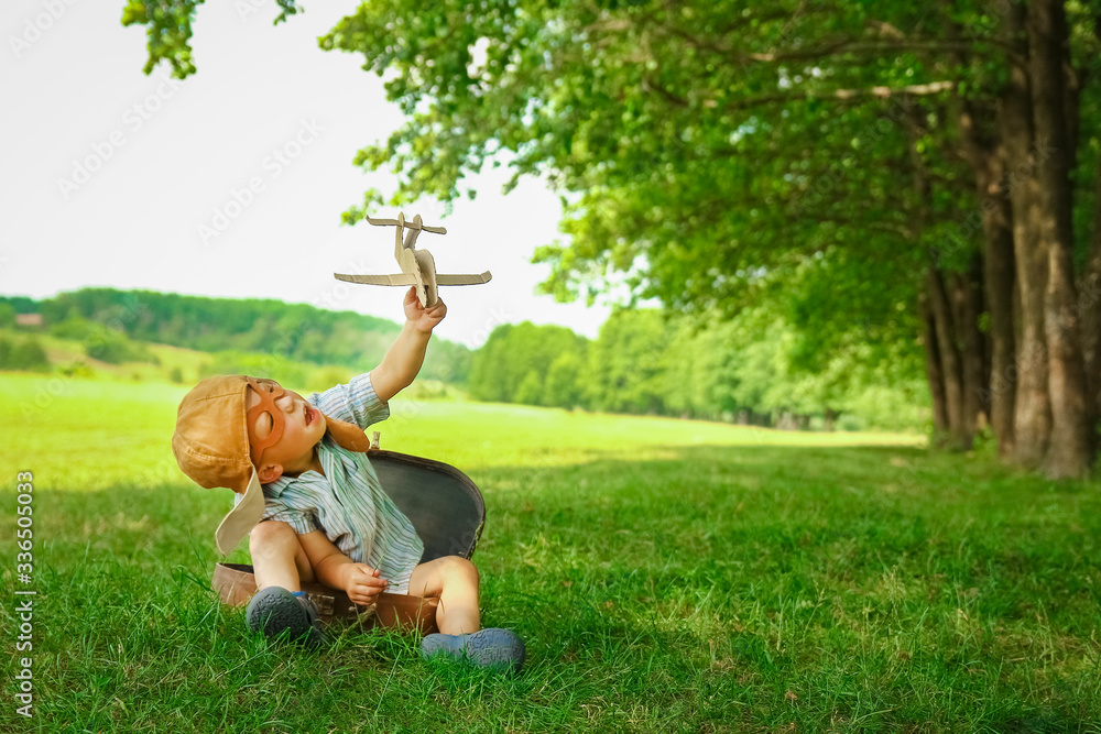 A Baby boy by the plane plays on nature in the park. Boy on vacation pilot. A Baby boy by the plane plays on nature in the park. Boy on vacation pilot.