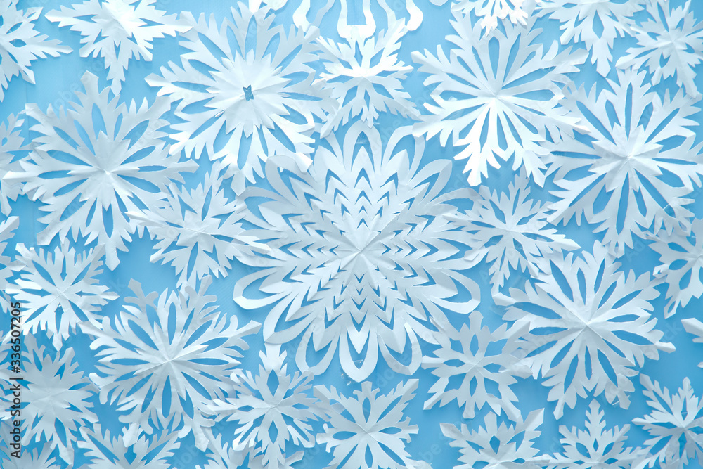 Christmas wallpaper with empty space for text . paper snowflakes blue background . Blue winter holiday background with handmade wooden snowflake .