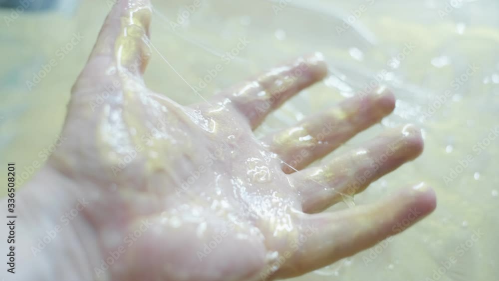 Closeup view of male hand holding green transparent slime, squeezing it Closeup view of male hand holding green transparent slime, squeezing it