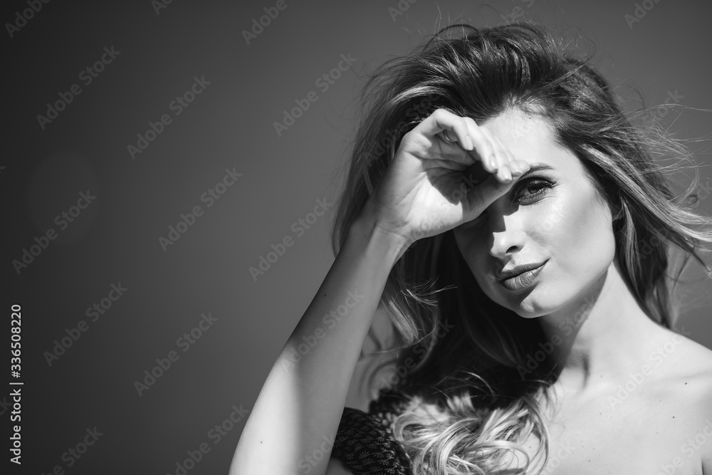 Close-up portrait of a beautiful romantic woman with sexy full lips and developing curls closes her hand from the sun. Black and white photo art. Soft selective focus. Close-up portrait of a beautiful romantic woman with sexy full lips and developing curls closes her hand from the sun. Black and white photo art. Soft selective focus.