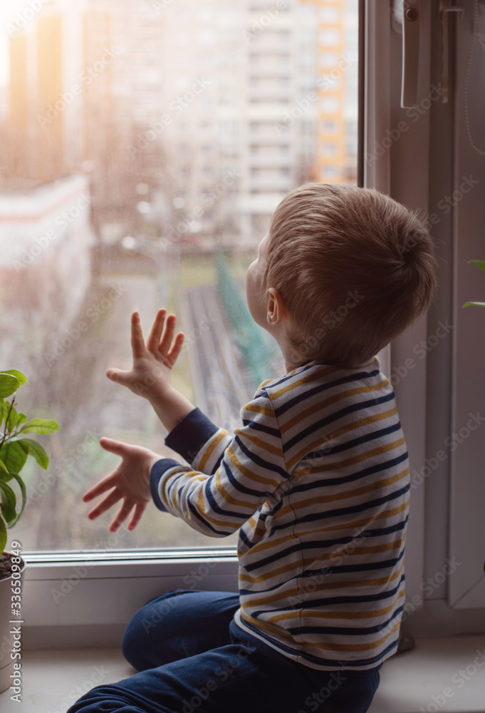 The boy is sitting on the window sill. Sad mood. The boy is sitting on the window sill. Sad mood.