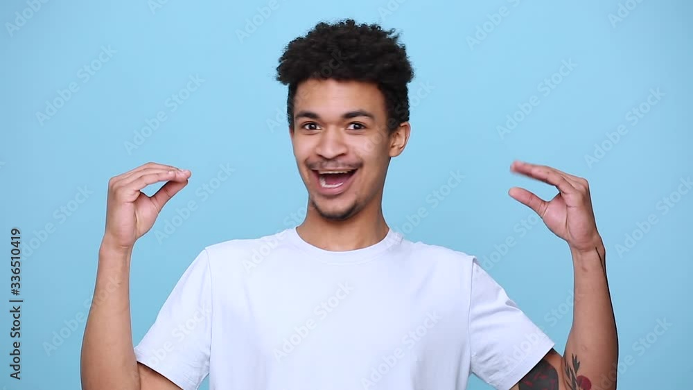 Fun african american young guy 20s in white t-shirt curly hair posing showing blah blah gesture ja jaja hands isolated on blue background studio portrait. People sincere emotions, lifestyle concept Fun african american young guy 20s in white t-shirt curly hair posing showing blah blah gesture ja jaja hands isolated on blue background studio portrait. People sincere emotions, lifestyle concept