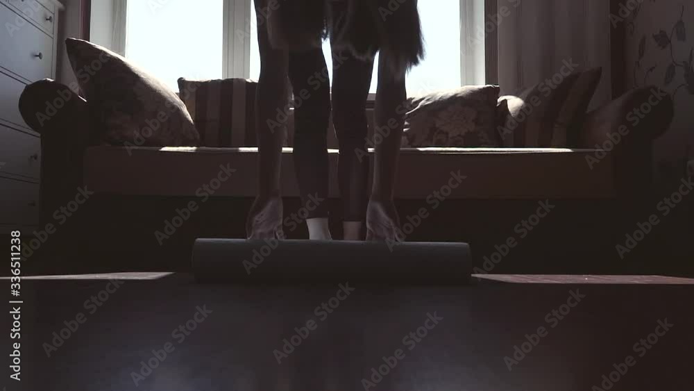 A young girl is arranging a yoga mat at home. Quarantine. Slow motion. A young girl is arranging a yoga mat at home. Quarantine. Slow motion.