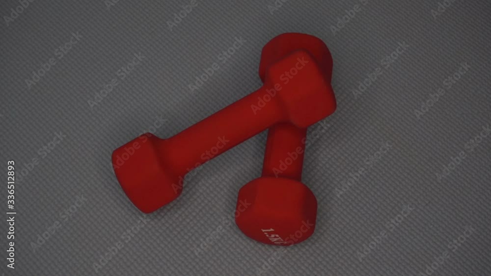 Red dumbbells lie on a yoga mat. Slow motion. Red dumbbells lie on a yoga mat. Slow motion.