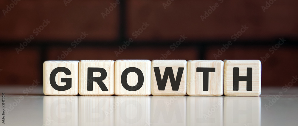 GROWTH - business financial concept on on a dark brick background. Wooden cubes with text GROWTH - business financial concept on on a dark brick background. Wooden cubes with text