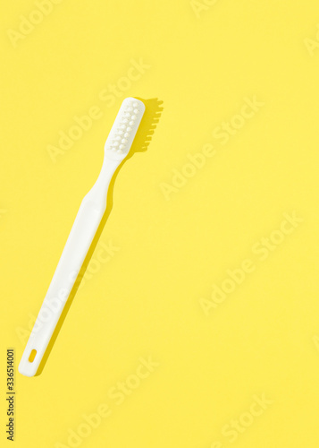 Toothbrush on yellow pastel background.