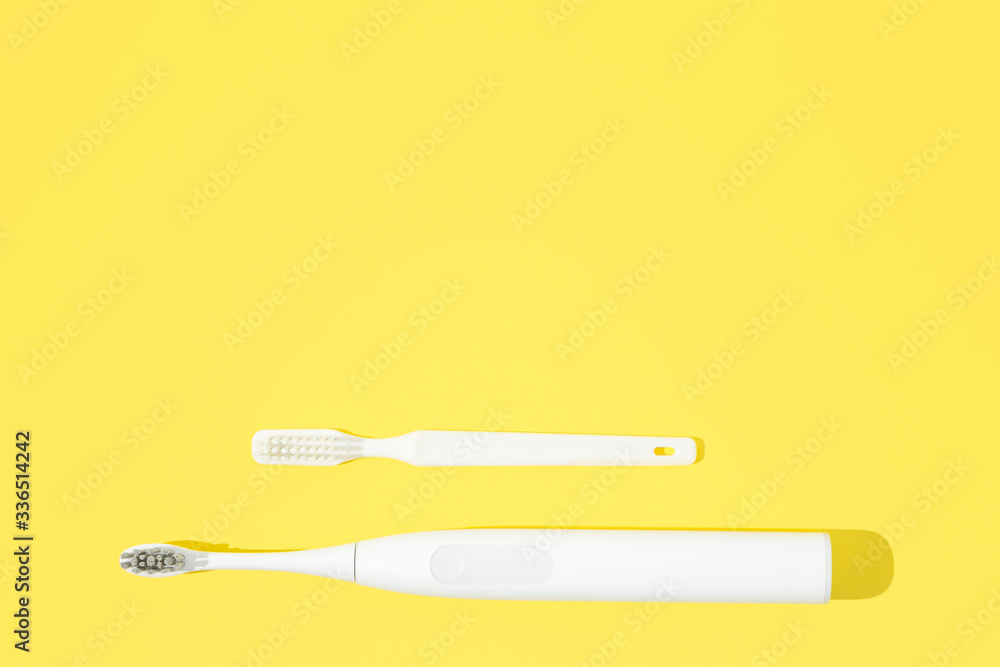 Obraz premium Two toohbrushes classic and sonic on bright yellow pastel background.