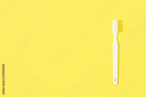 Toothbrush on yellow pastel background.