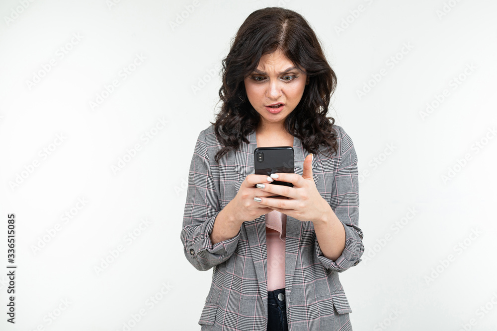 brunette girl in a gray jacket with a phone in his hands communicates on an isolated white background brunette girl in a gray jacket with a phone in his hands communicates on an isolated white background