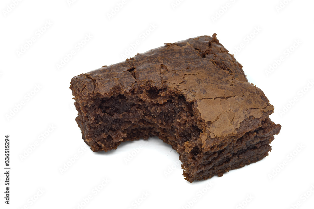 A close up of a chocolate brownie cake with a bit taken out isolated on a white background