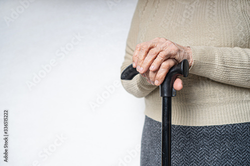 Mobility problems in old people. Wrinkled hands holding a walking stick.