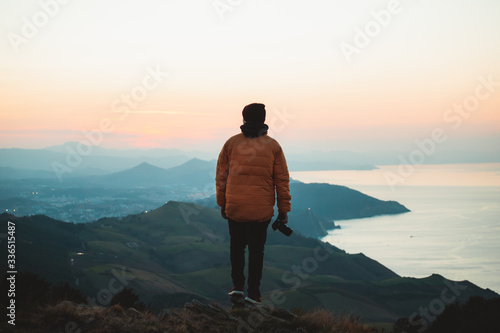 Young man holding a camera watching the sunset from Jaizkibel Mount photo
