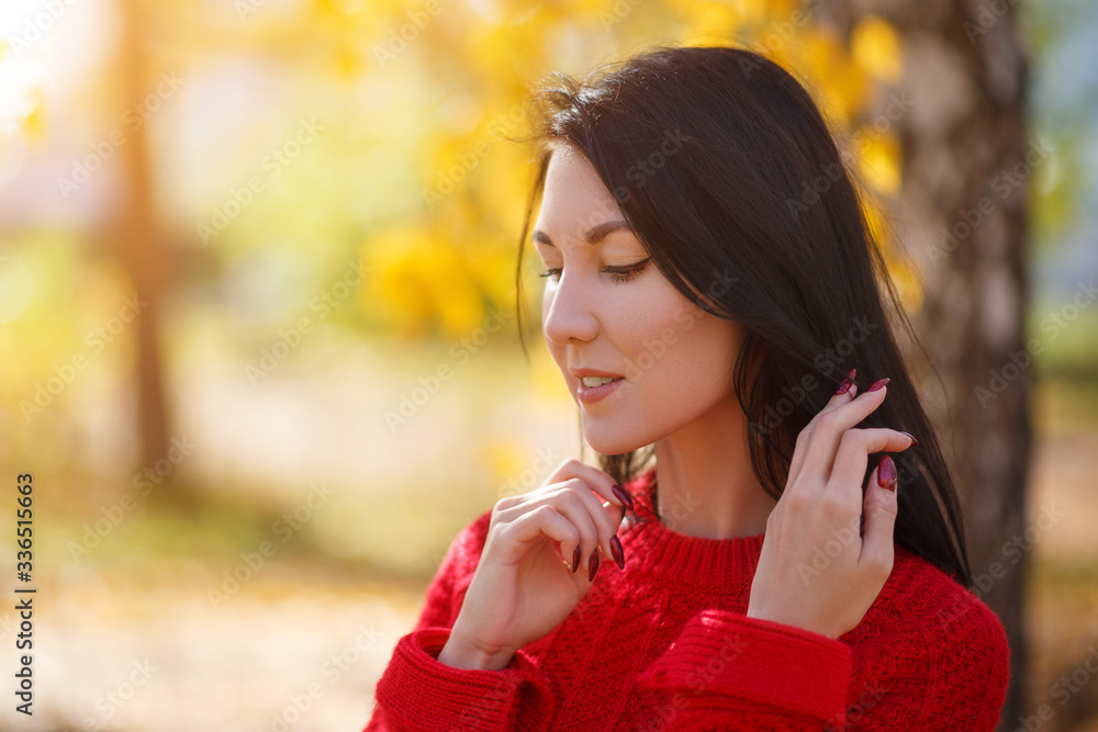 Autumn portrait of a young brunette girl woman in a red sweater