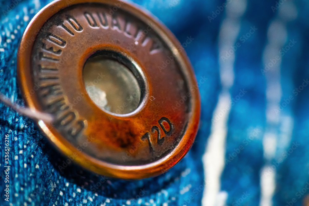 Close up of a metal button on a pair of jeans