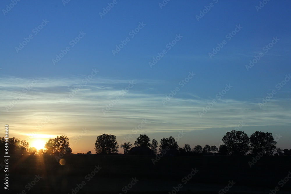 Sunset with a flare on the horizon under the blue sky