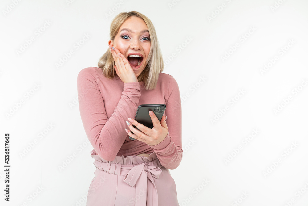 surprise happy girl in pink clothes surfing the internet on the phone on a white background surprise happy girl in pink clothes surfing the internet on the phone on a white background
