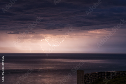 Distant yellow lightnings with reflections over the Black sea with an abandoned concrete building in the foreground