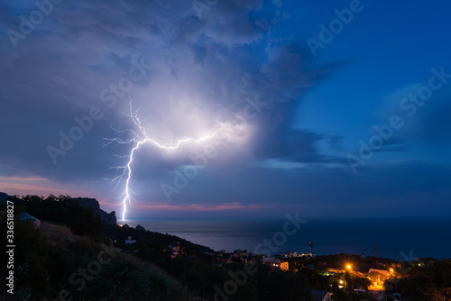 A powerful lightning bolt over the Black sea coast with a small town