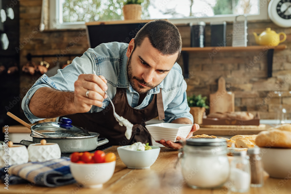 Young man making dipping sauce while preparing food in the kitchen. Young man making dipping sauce while preparing food in the kitchen.