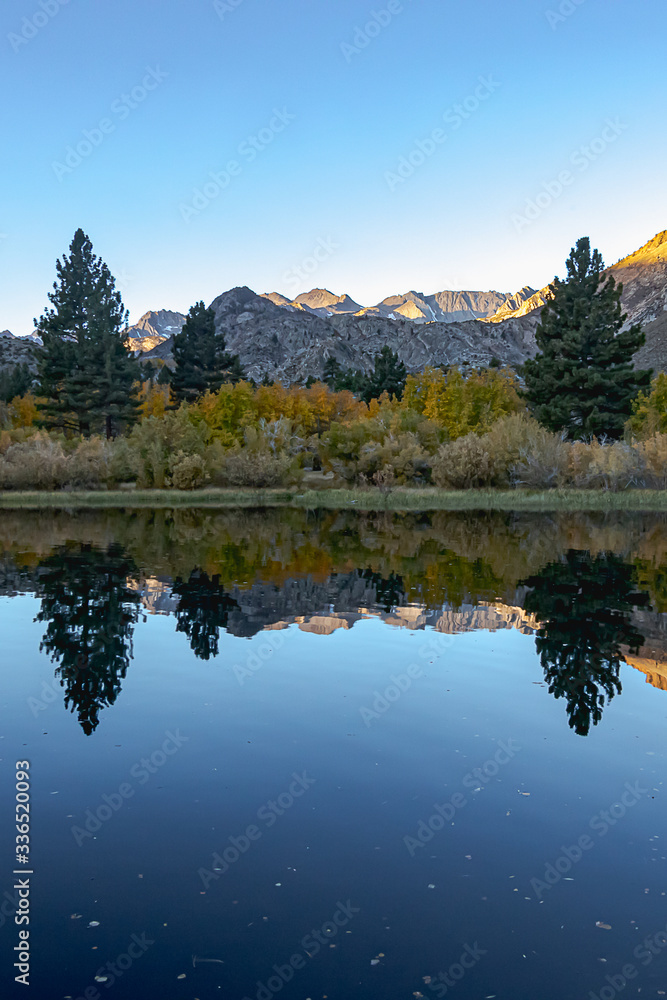 reflecctive mountain lake with pines aspens grass and mountain