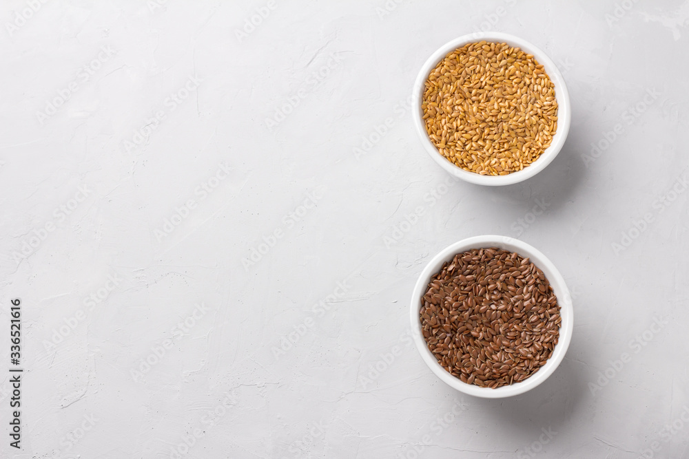 Golden and brown raw flax seeds in white bowls on a gray textured background, top view, space. healthy vegan superfood Golden and brown raw flax seeds in white bowls on a gray textured background, top view, space. healthy vegan superfood