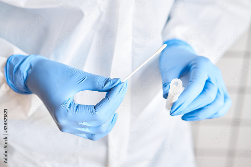 Doctor holding swab test tube for 2019-nCoV analyzing. Coronavirus test. Blue medical gloves and protective face mask for protection against covid-19 virus. Coronavirus and pandemic. Doctor holding swab test tube for 2019-nCoV analyzing. Coronavirus test. Blue medical gloves and protective face mask for protection against covid-19 virus. Coronavirus and pandemic.
