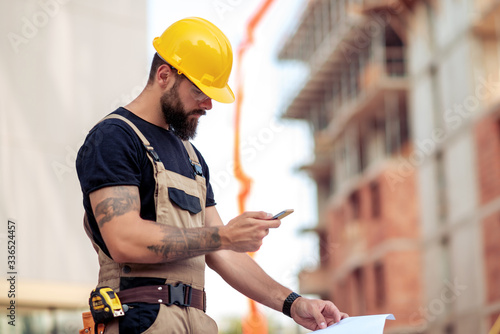 Vászonkép Engineer holding smart phone at construction site