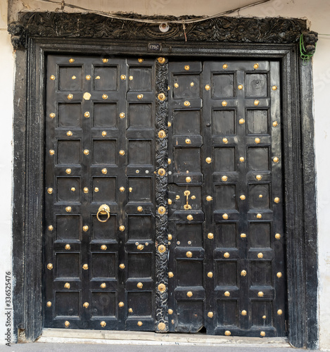 a famous traditional wooden door in Stone Town. the door is brown with gold incrustation