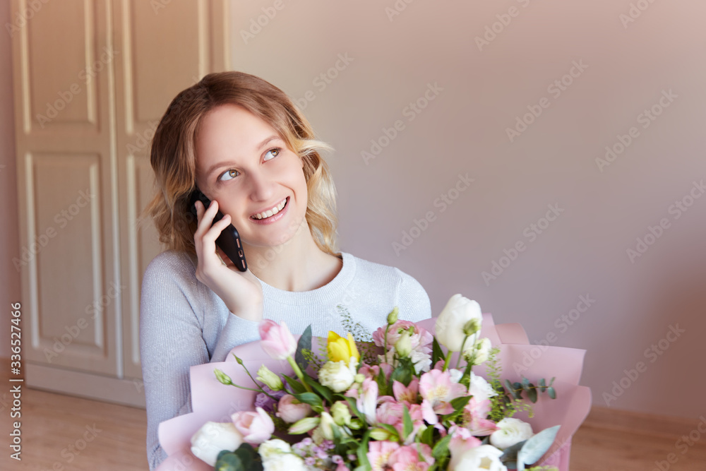 Young blonde girl talking phone bouquet of flowers as a gift. Flower delivery birthday gift for women. Young blonde girl talking phone bouquet of flowers as a gift. Flower delivery birthday gift for women.