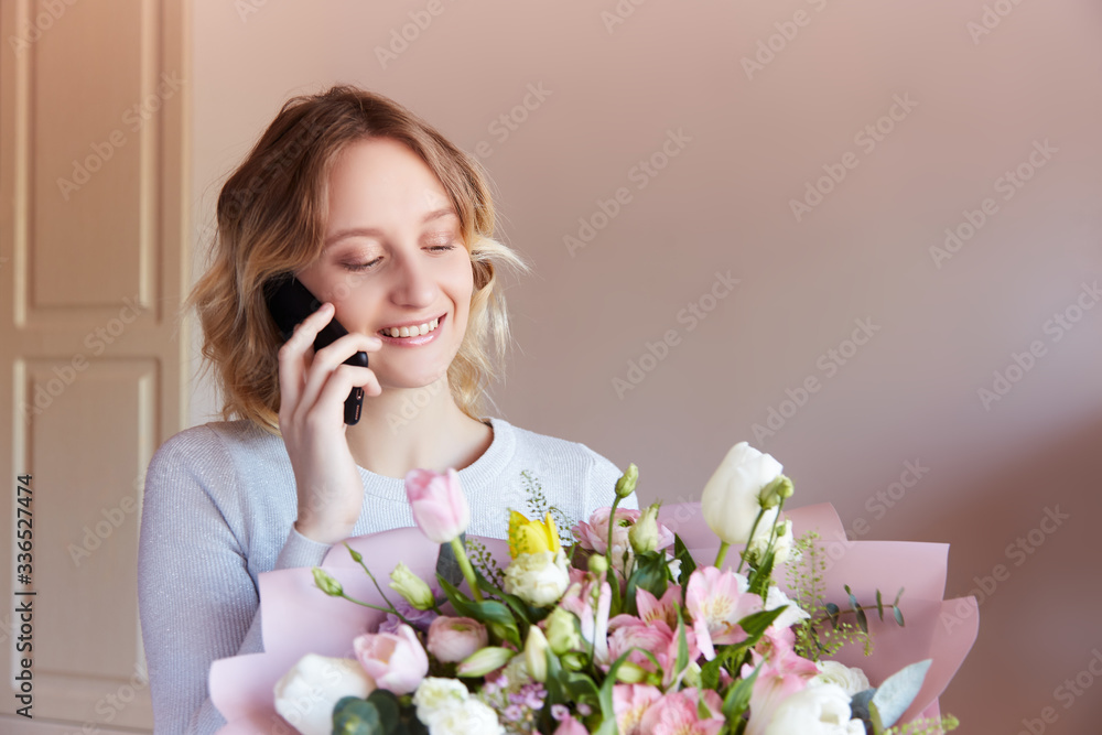 Young blonde girl talking phone bouquet of flowers as a gift. Flower delivery birthday gift for women. Young blonde girl talking phone bouquet of flowers as a gift. Flower delivery birthday gift for women.