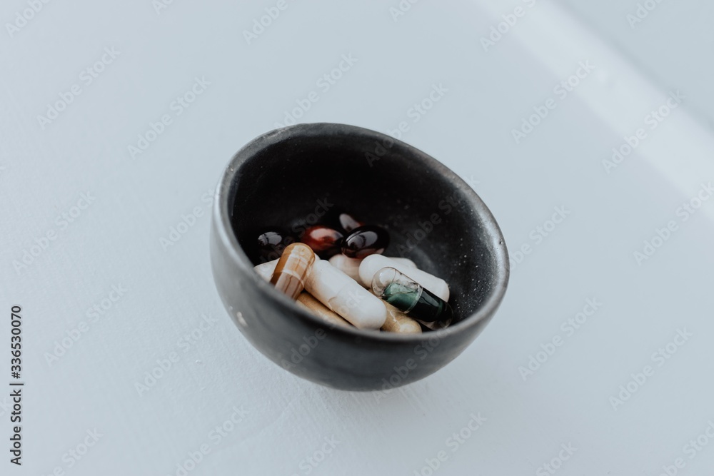 Bowl of vitamins or supplements in a black bowl on white background