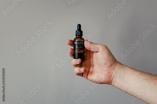 Hand holding beard oil in amber bottle 