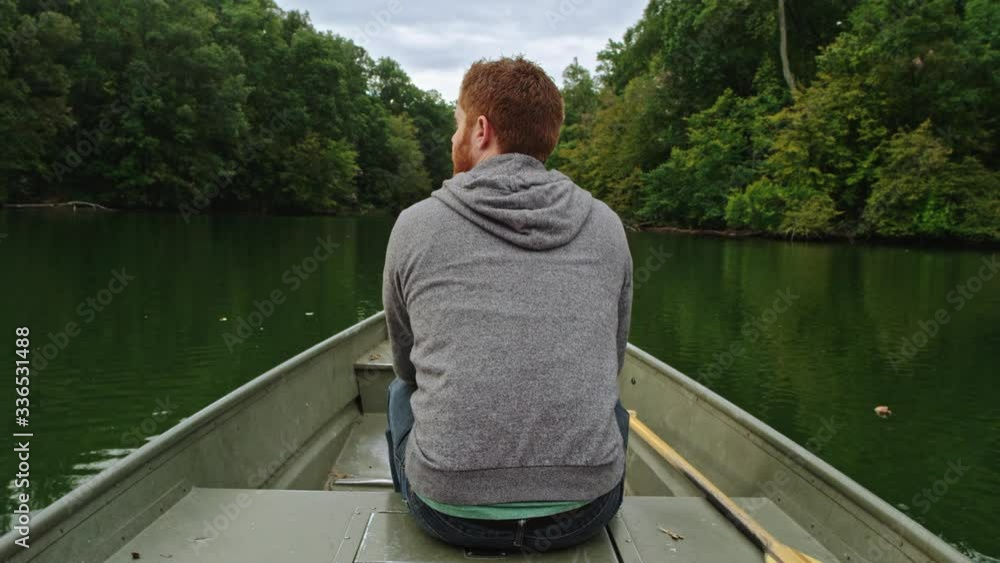 Man paddles boat on calm water Man paddles boat on calm water