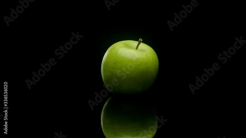 A green apple rotating on a black background photo