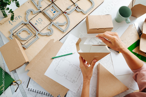 Woman holding box with a hole above her workplace photo