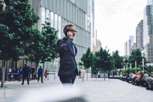 Mature businessman calling by smartphone in city