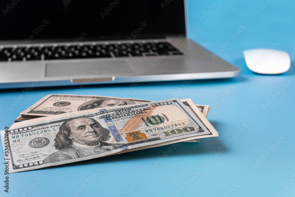 The concept of working from home during a coronavirus epidemic. People work remotely. Laptop and banknotes on a blue background. Covid-19 The concept of working from home during a coronavirus epidemic. People work remotely. Laptop and banknotes on a blue background. Covid-19