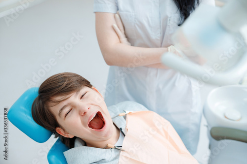 Patient in dental chair. Teen boy having dental treatment at dentist's office. Healthy teeth, dental care concept.